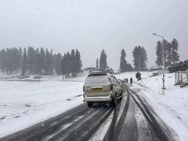 Gulmarg: Vehicles move on a road amid light snowfall, in Gulmarg. (PTI Photo) (...