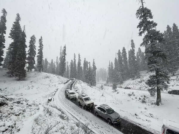 Gulmarg: Vehicles move on a road amid light snowfall, in Gulmarg. (PTI Photo) (...