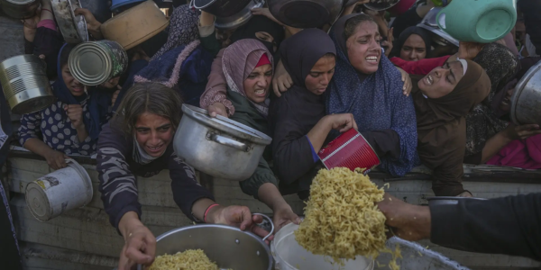 Palestinian girls struggle as they get donated food at a distribution center in Khan Younis (Pic credit: AP)