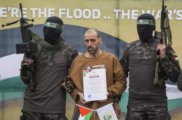 Eli Sharabi stands on a stage escorted by Hamas fighters before being handed over to the Red Cross in Deir al-Balah, central Gaza Strip, Saturday February 8, 2025. (AP)