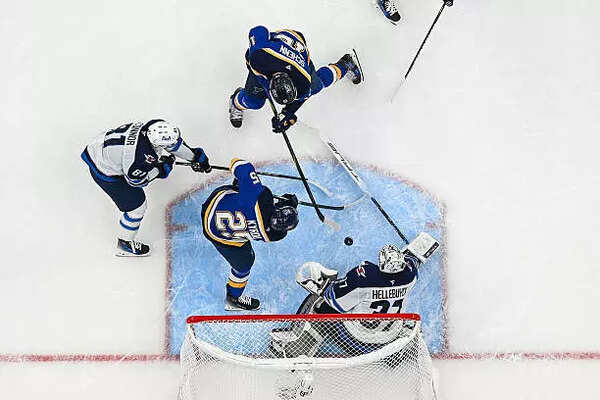 Connor Hellebuyck #37 of the Winnipeg Jets defends the net against Jordan Kyrou #25 and Brayden Schenn #10 of the St. Louis Blues in the second period of Game Four