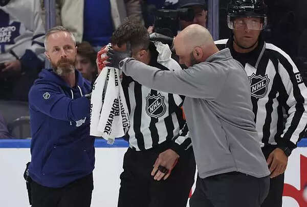 ​Referee Chris Rooney is helped off the ice after being injured​