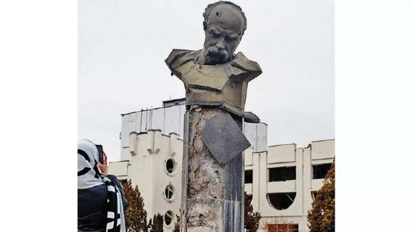 A woman in a town near Kyiv photographs Ukrainian poet Taras Shevchenko’s statue, which was damaged in the early days of the war with Russia