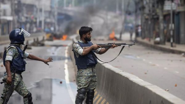 A policeman aims his weapon at protesters during a curfew imposed following violence during protests against Sheikh Hasina and her government, in Dhaka, Bangladesh.