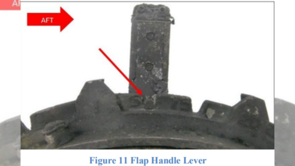 This image documents the condition of the flap handle assembly (Figure 11), which suffered significant thermal damage due to the post-crash fire. Despite the damage, the handle was firmly set in the 5-degree position, which is consistent with a normal takeoff configuration. (Image credit: Preliminary Report AAIB) (Image credit: Preliminary Report AAIB)