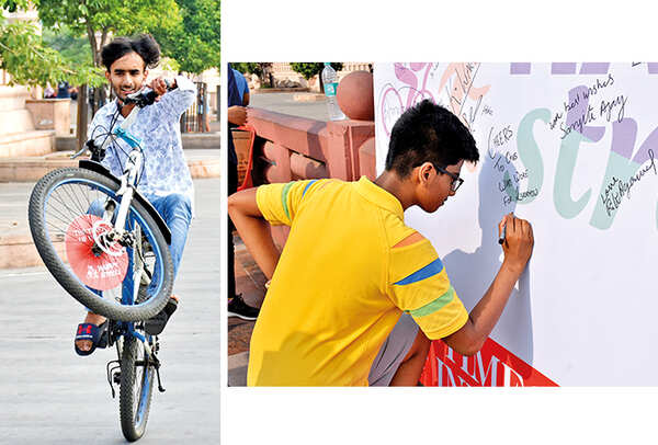 Amaan Khan performs stunt on the cycle while a youngster writes his thoughts on the Wall of Fame put up at Happy Streets (BCCL/ Vishnu Jaiswal)