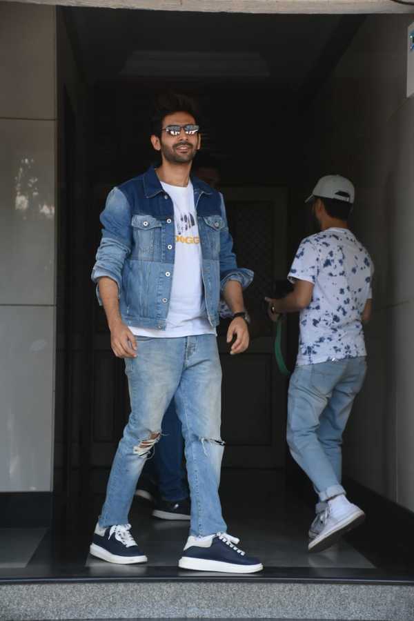 Kartik Aaryan dressed in orange shirt and blue shredded jeans and