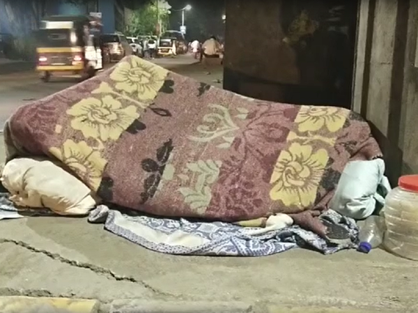 Girl sleeping on a footpath.
