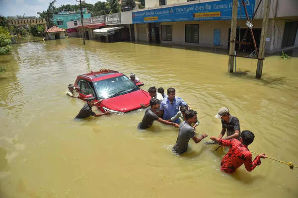 Bengaluru_ Rescuers try to get a car out of the flooded Rainbow Drive Layout after ....