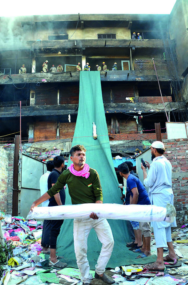 बांसमंडी में आग लगने के बाद जली दुकानों से सामान हटाते दमकलकर्मी बांसमंडी में आग पर काबू पाया गया, 1,150 दुकानें पूरी तरह जलकर खाक घोषित