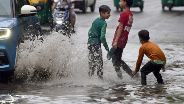 Children play on a waterlogged road during rain. PTI photo