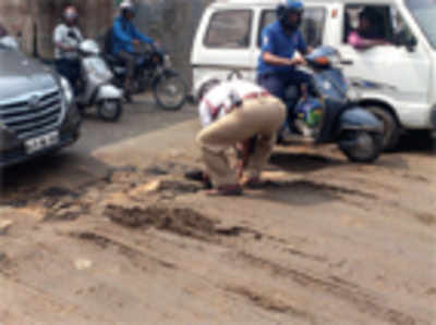 Traffic cops carry cement slabs and stones to fill gaping pothole
