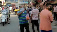 Delhi: Man showers flower petals on people standing in queue outside liquor shop 