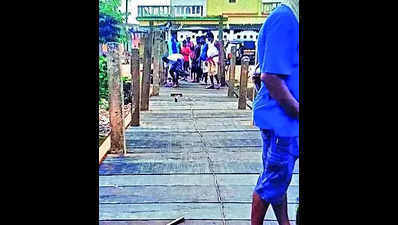 Villagers build bridge with wooden planks over canal