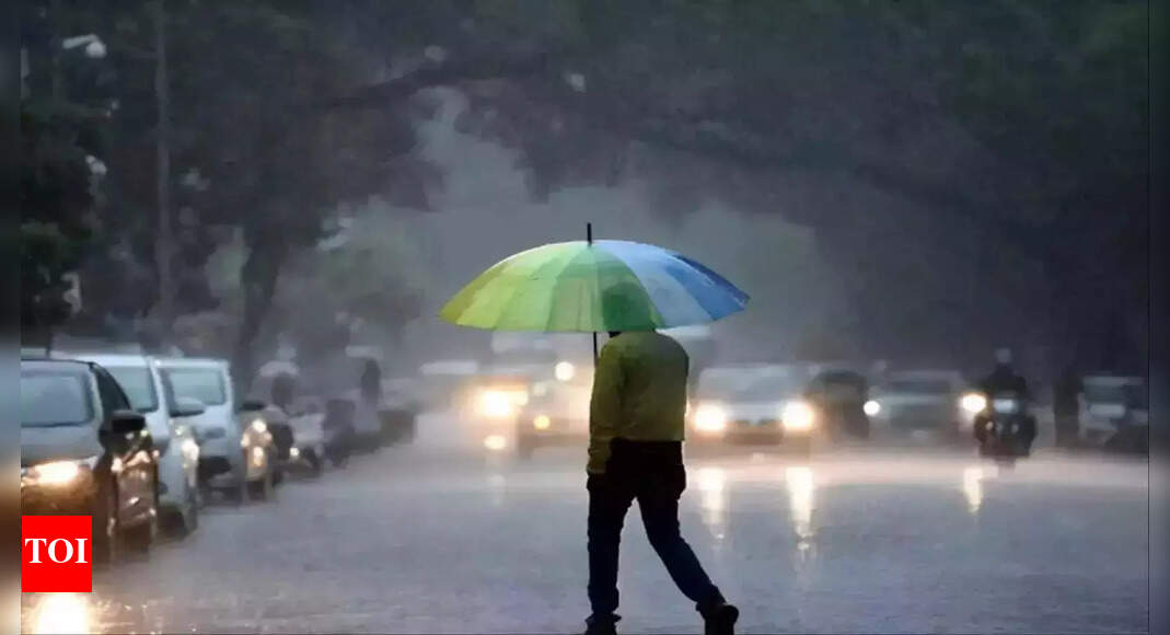 Bengaluru city street with overcast skies, light rain, and pedestrians carrying umbrellas during mild November weather