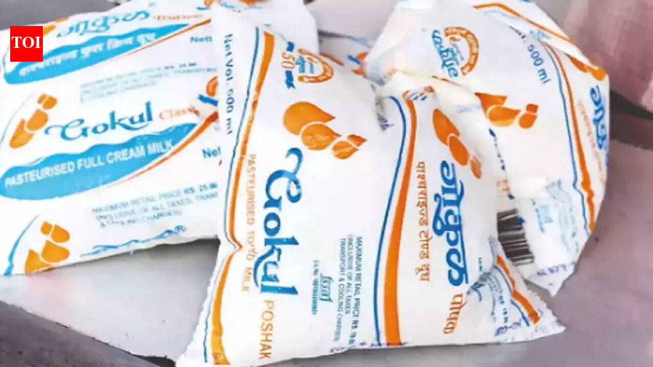 A full glass of frothy buffalo milk next to a Gokul milk packet, symbolizing the price increase.