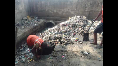 Sanitation workers clean drains without safety gear