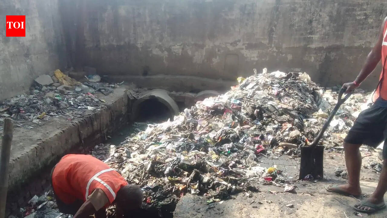 Sanitation workers clean drains without safety gear