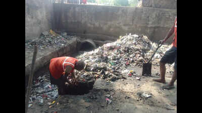 Sanitation workers clean drains without safety gear
