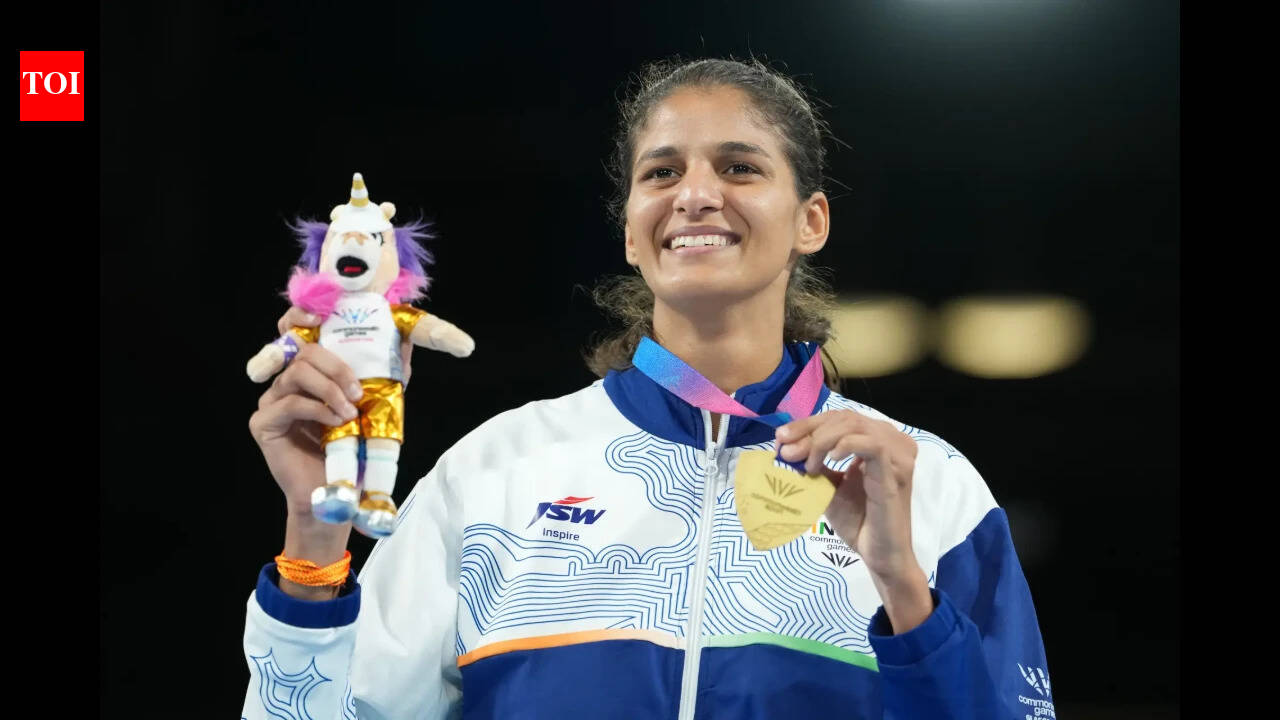 A smiling woman holding a unicorn toy and a gold medal.