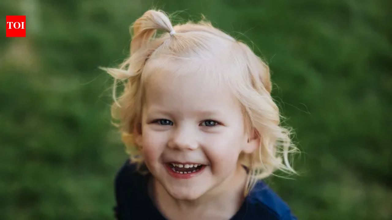 A young blonde girl smiling outdoors.