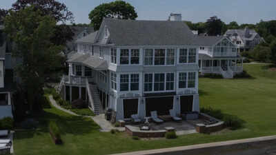 A glass-wrapped Connecticut waterfront home with views of Long Island Sound went to auction with bidding starting at $2.1 million; the lighthouse-inspired house sits directly on the shoreline