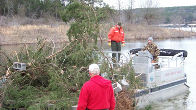 Nebraska workers cut 150 trees from crowded lake banks and sank them at 16 underwater locations; the September 2026 project is building shelter for young fish in two lakes without using concrete reefs