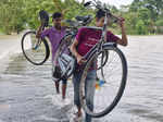 People carry their bicycles as they wade through flood waters