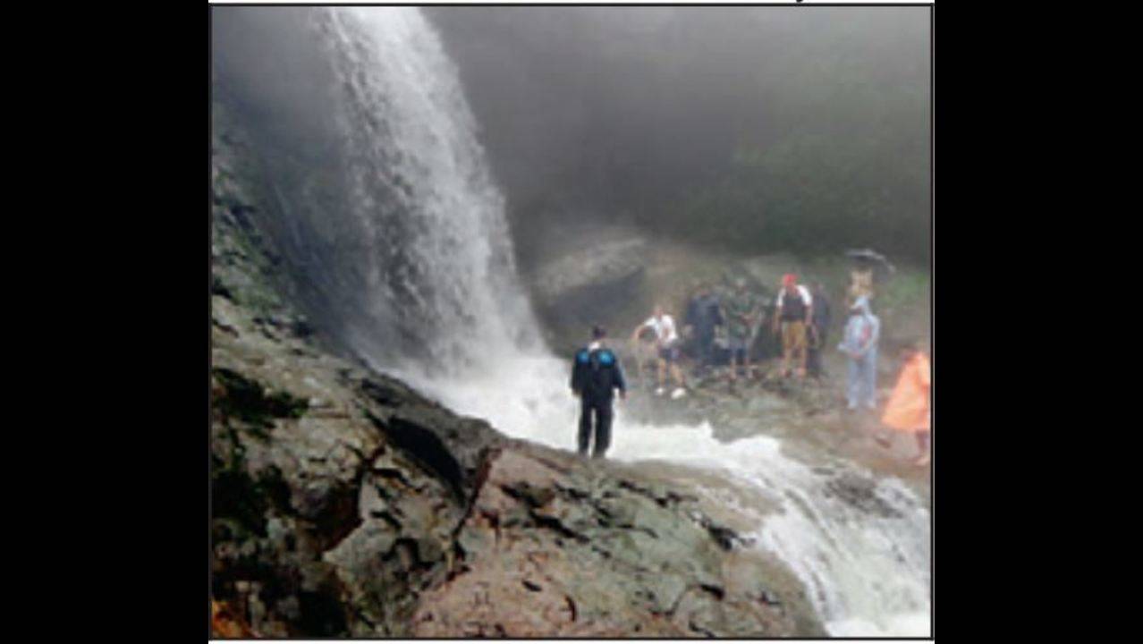 Young men cool themselves off in a waterfall as temperatures