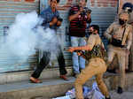 A police officer fires tear gas shell towards stone-pelters