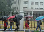 Office-goers use umbrellas during heavy rain