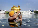 A Sikh man along with his child takes a dip in the sacred pond