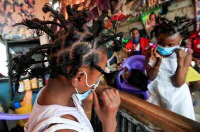 Martha Apisa, 12, adjusts her face mask after plaiting with the 'coronavirus' hairstyle, in Nairobi, Kenya (Reuters)