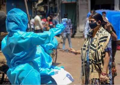 A healthcare worker conducting thermal screening at Dharavi slum area in Mumbai on Tuesday