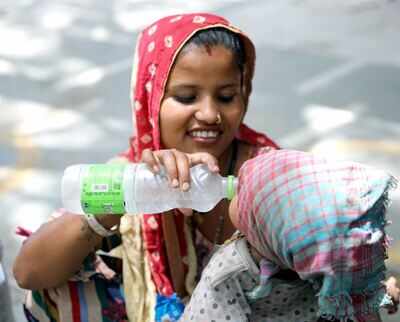 A woman gives drinking water to his child during the prevailing heatwave conditions in Delhi on Thursday. (ANI Photo)