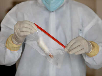 FILE PHOTO: A doctor wearing a protective suit seals a bag containing a swab sample vial, at a testing center, in New Delhi. REUTERS