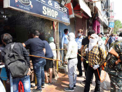 FILE: A health worker sanitizes outside the wine shop at Shivpuri in Delhi. TOI
