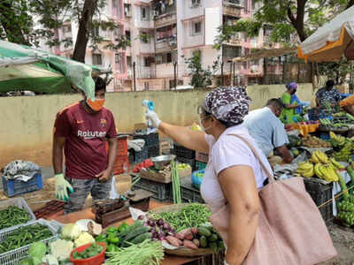 A volunteer uses temperature gun to screen vendors at I C Colony, Borivli