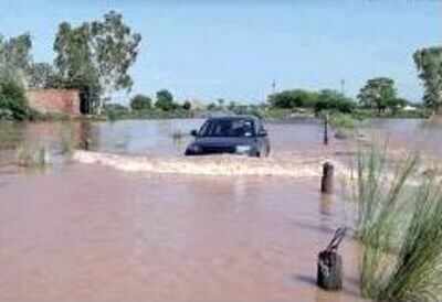 A car wades through a flooded road at Gujra Duddhan village