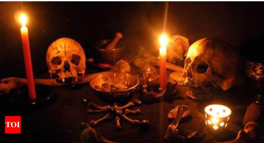  A dimly lit room with a table covered with skulls, bones, and candles representing the search query 'Symptoms of black magic in humans'.