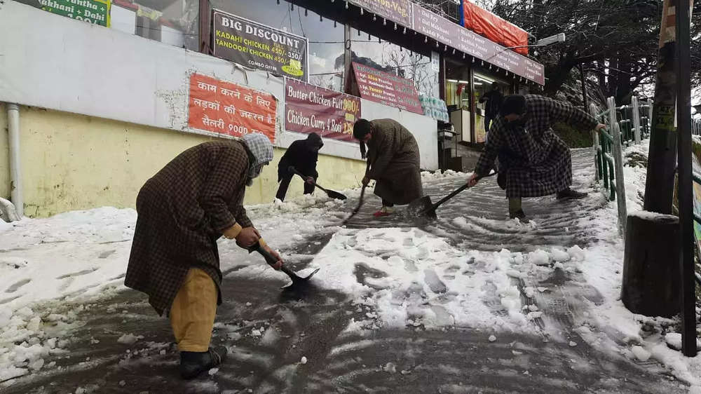 Locals clear the snow from the road in Shimla