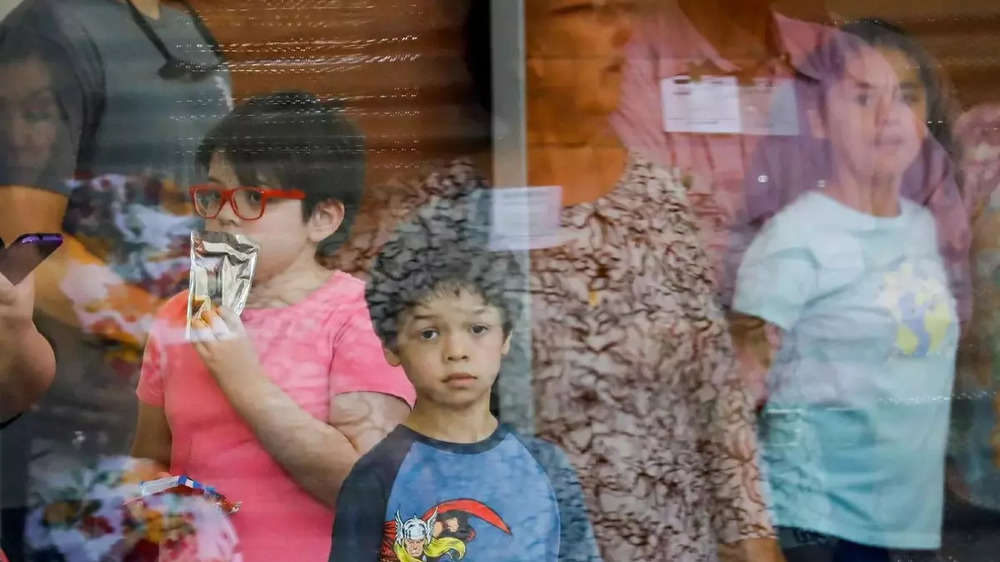 ​A child looks on through a glass window from inside the Ssgt Willie de Leon Civic Center, where students had been transported from Robb Elementary School after a shooting, in Uvalde, Texas.