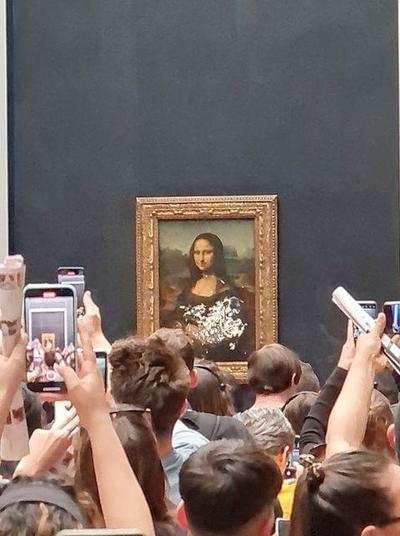 Man dressed as an old woman throws cake at Mona Lisa portrait