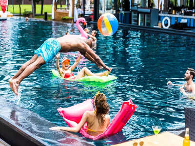 Four teenage girls in bikinis leaping into outdoor pool, Stock