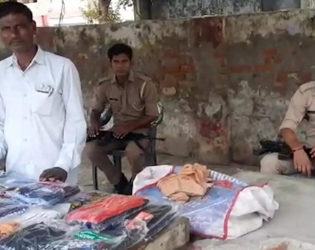 
Street vendor guard by two gunners who sells clothes on roadside
