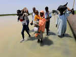 People cross the water during a flood in Al-Managil locality in Jazeera State