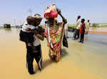 People cross water during flood in Al-Managil locality in Jazeera State