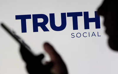The Truth social network logo is seen displayed behind a woman holding a smartphone in this picture illustration taken Truth Social bills itself as Trump's answer to platforms like Twitter, which the former president used as a loud political bullhorn until he was ejected from it after a mob he had egged on assaulted the US Capitol in January 2021. banner img