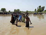 Victims of unprecedented flooding from monsoon rains line up to receive relief a...