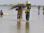 Flood-affected people wade through a flooded area caused by heavy rain, in Qamba...